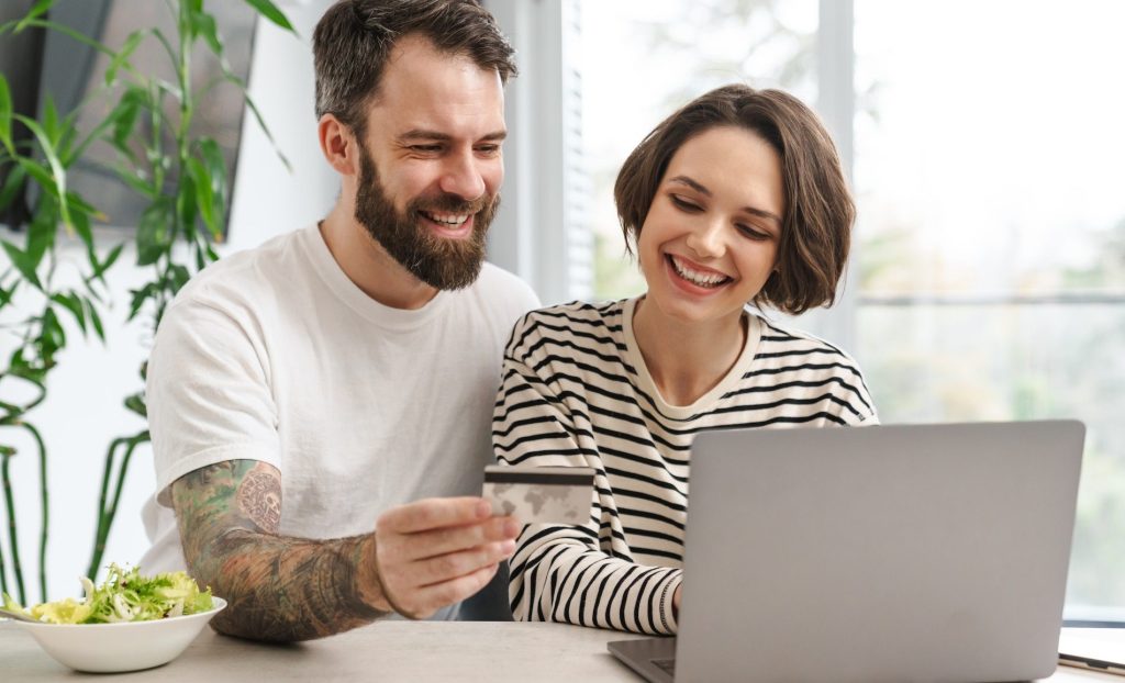 Portrait of a cheerful couple shopping online with laptop computer